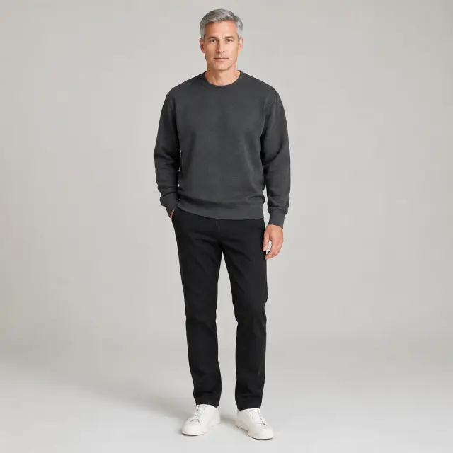 Adult model with short straight gray hair wearing a plain charcoal sweatshirt in a neutral studio.