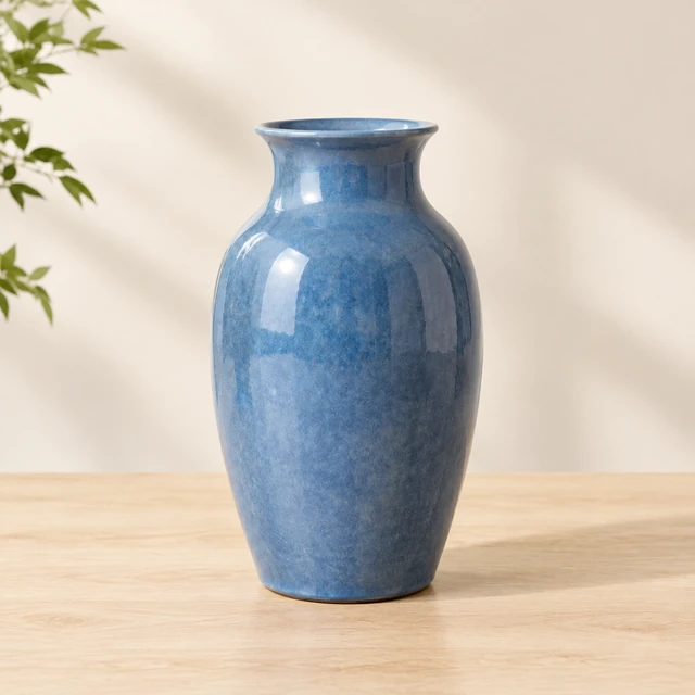 Same matte blue ceramic vase on a pale wood studio table against a warm wall, ready for the listing.