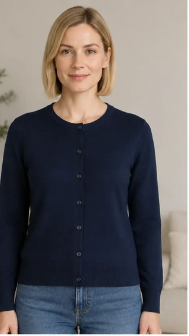 She lifts a navy cardigan and restyles it twice in front of the mirror: layered over a knit, then over a shirt.