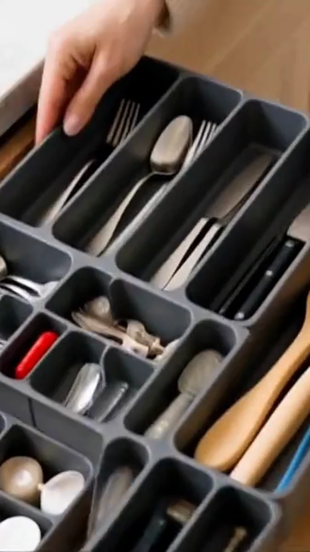 Hands organize gray drawer dividers and utensils in a vertical home organization video frame.