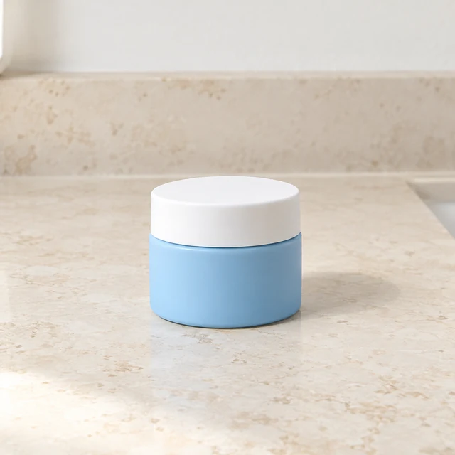 A plain sky-blue moisturizer jar with a white lid on a clean bathroom counter.