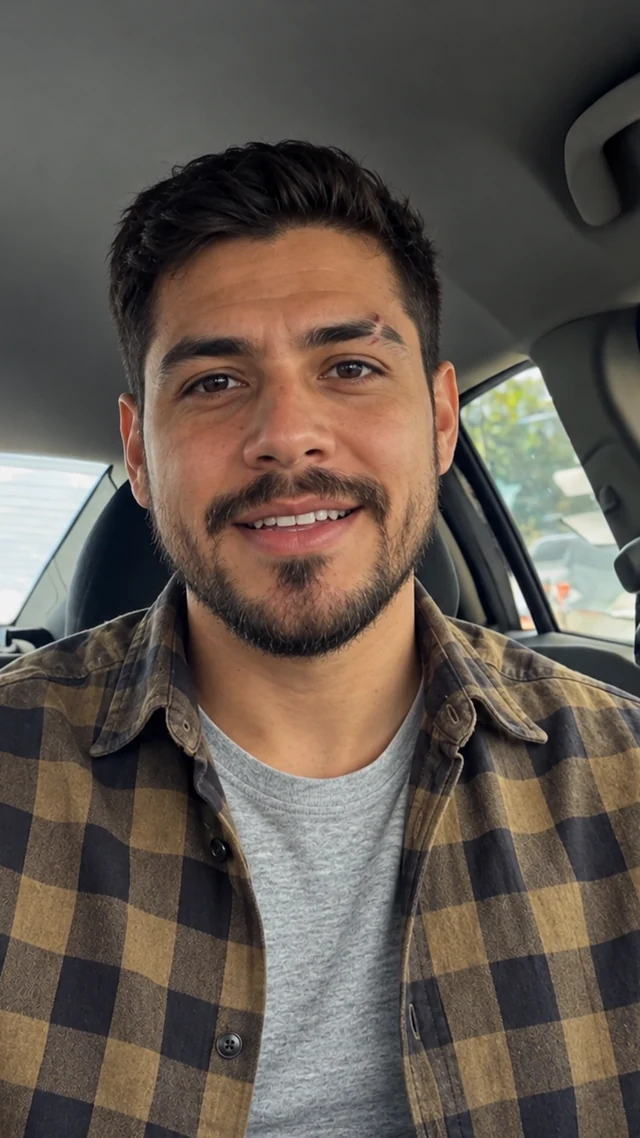 an adult Latino man in his thirties in a car setting speaks to camera with empty hands.