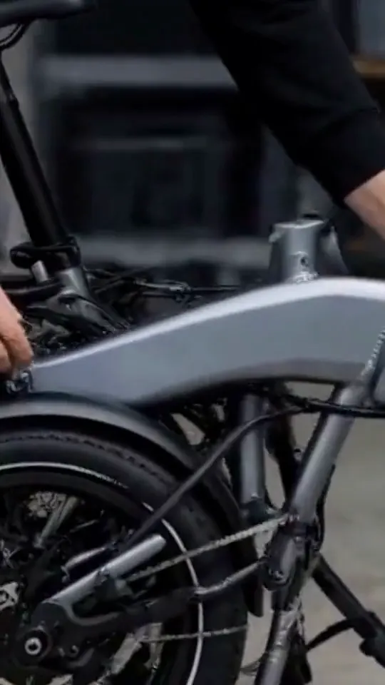 Hands unfold a black folding electric bicycle and inspect its hinge.