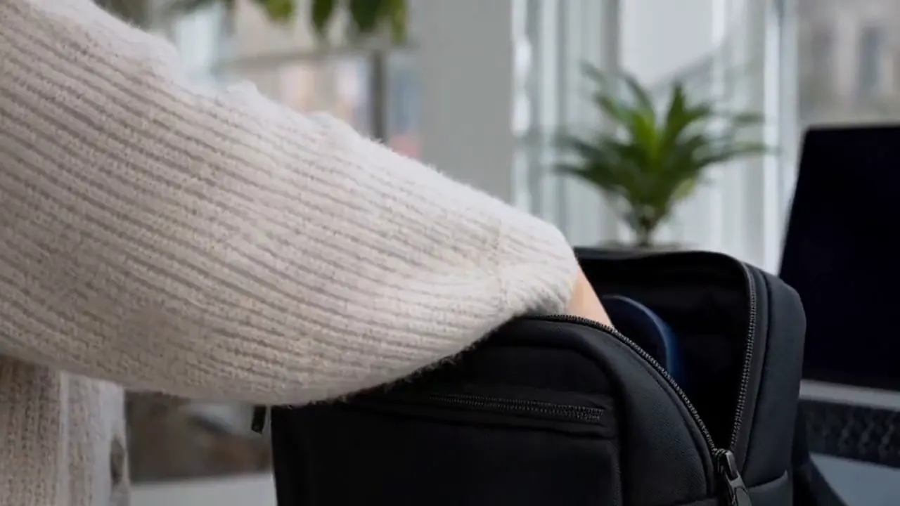 Hands inspect dark blue headphones and place them into a commuter bag.