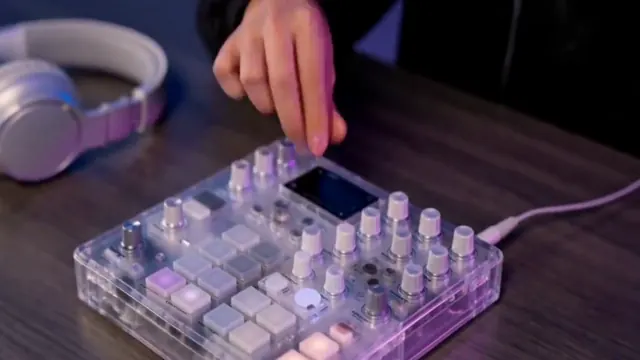 Hands press a transparent synthesizer on a neon desk and put on headphones.