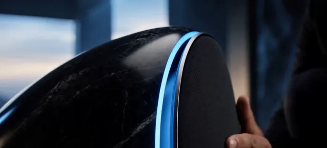 Close view of a black marble speaker with a glowing blue edge in a dark room