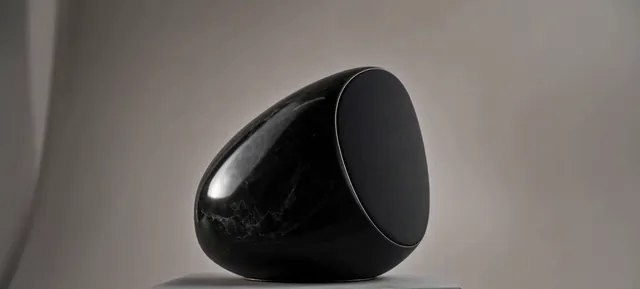 Black marble speaker on a stone plinth against a soft gray studio background