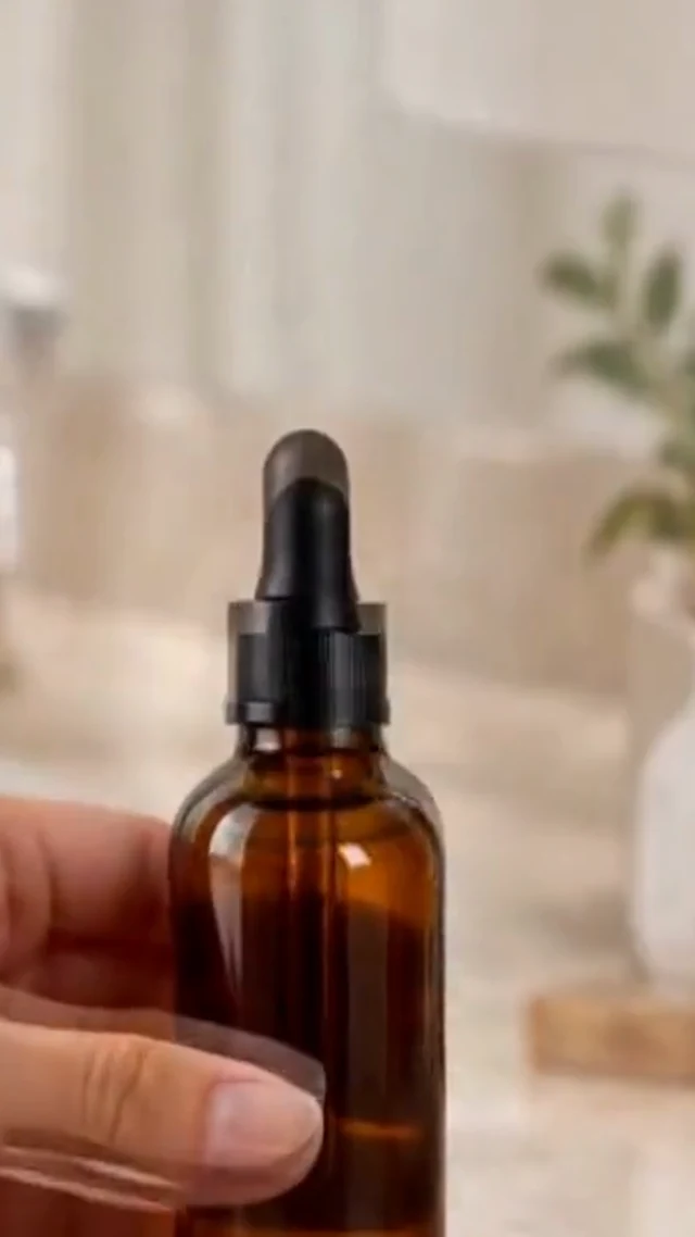 A real vertical frame from the local beauty routine clip showing an amber serum bottle and hand.