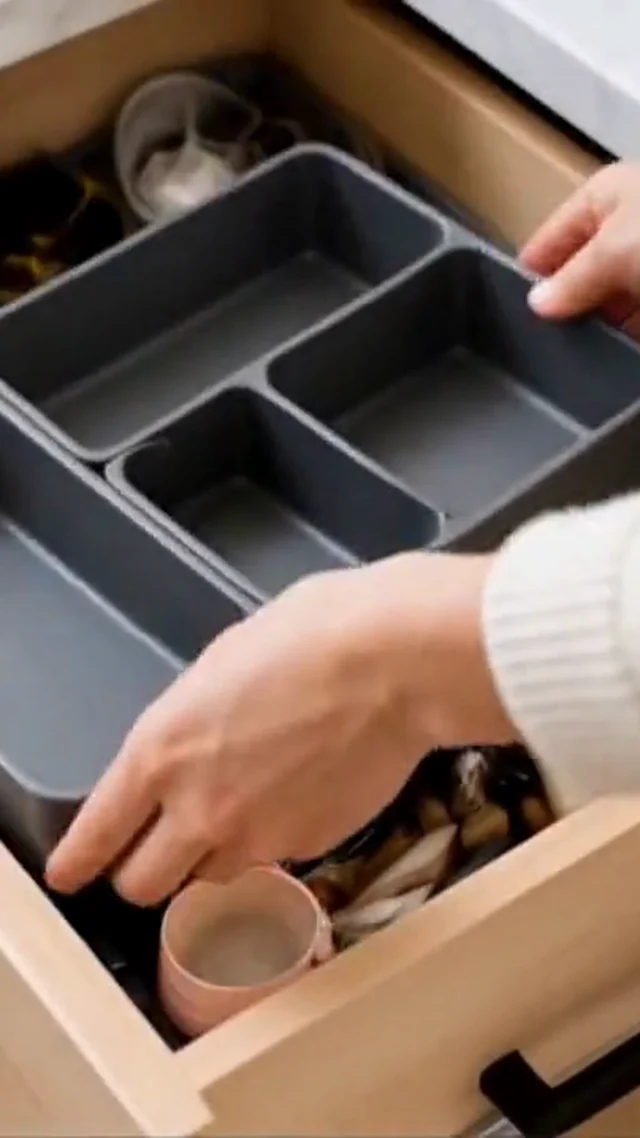 Hands organize gray drawer dividers and utensils in a vertical home organization video frame.