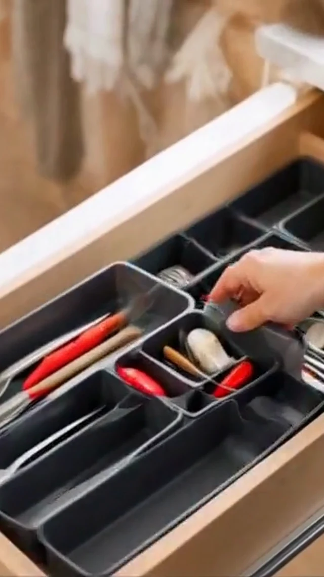 Hands organize gray drawer dividers and utensils in a vertical home organization video frame.