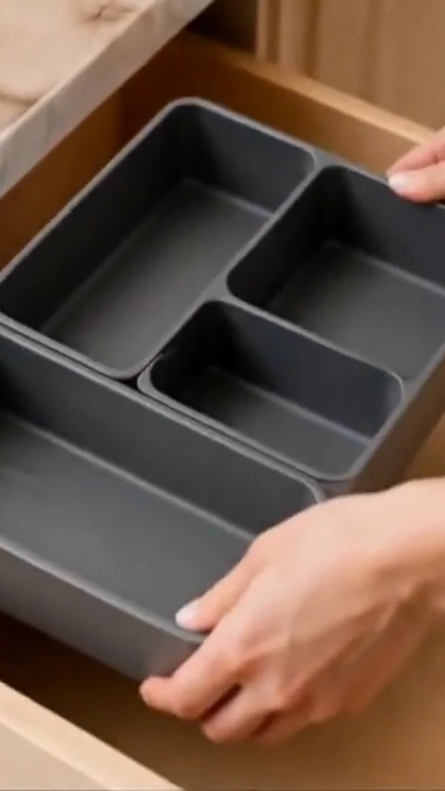 Hands organize gray drawer dividers and utensils in a vertical home organization video frame.
