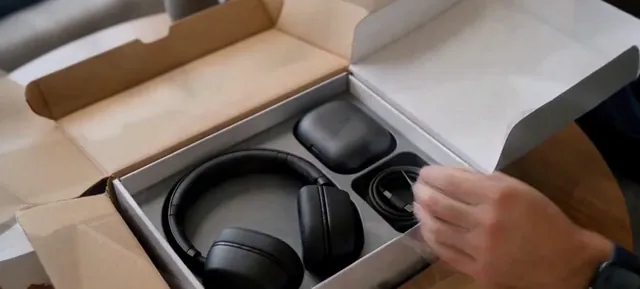 Over-ear headphones and a charging case inside an open gray box