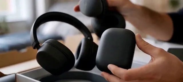 Hands holding black over-ear headphones above an open box
