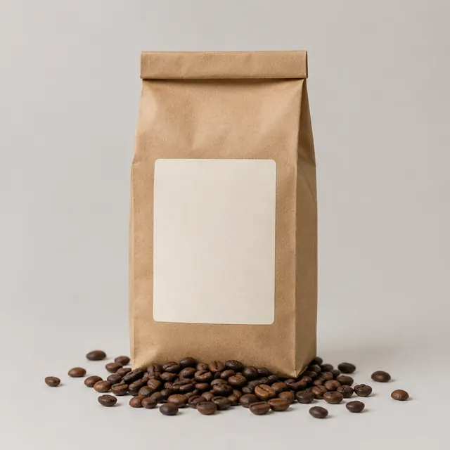 Kraft paper coffee bag with a blank label and whole coffee beans on a light studio background