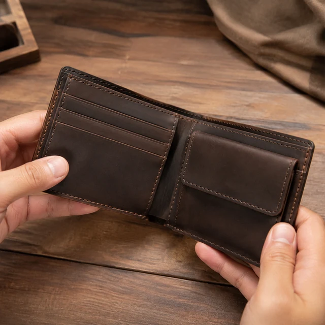 Adult hands open a leather wallet to show stitching and card slots