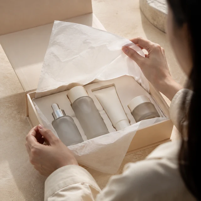 Adult opens a skincare set and lifts the tissue paper.