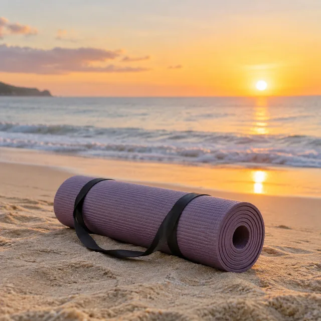 Rolled yoga mat on a beach at sunrise.