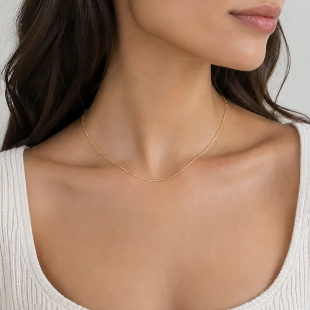 Fine chain necklace worn at the collarbone.