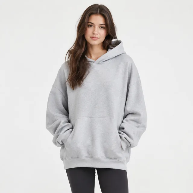 Model wearing an oversized hoodie in a bright studio, front view.