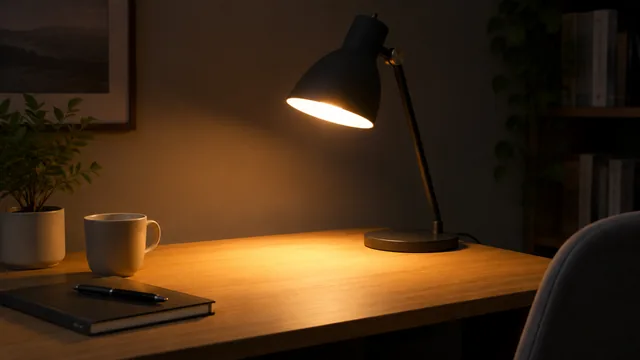 Desk lamp just switched on in a dark room, a warm pool of light on the desk.
