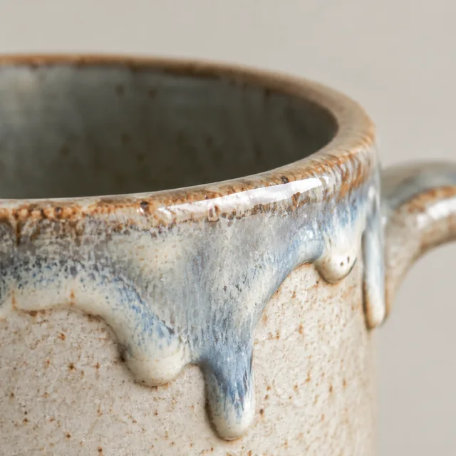 Macro close-up of glaze drips on a handmade ceramic mug rim.