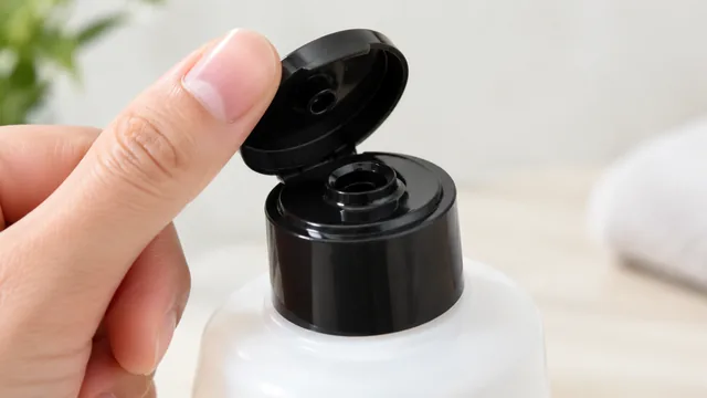 Close-up of a flip-top bottle cap being opened with a thumb.