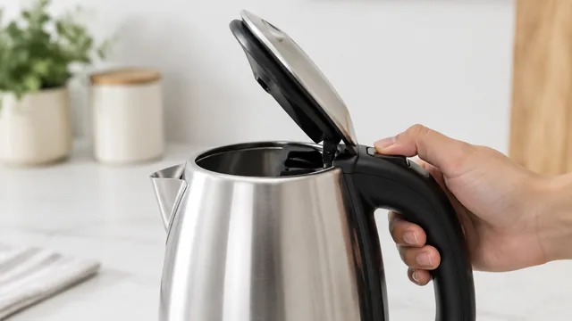 Thumb pressing the lid button of an electric kettle, lid popping open.