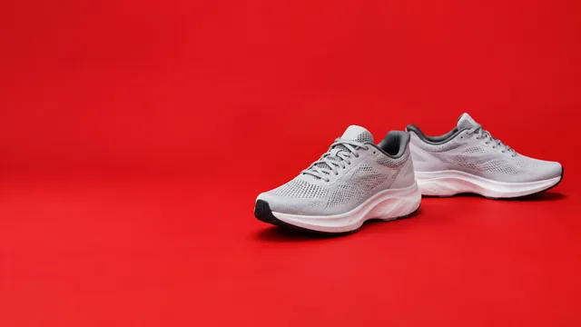 Running sneakers on a bold red backdrop with open space.