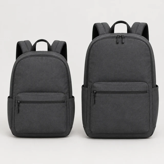 Two unbranded charcoal commuter backpacks in matching fabric, one compact and one larger, arranged side by side.