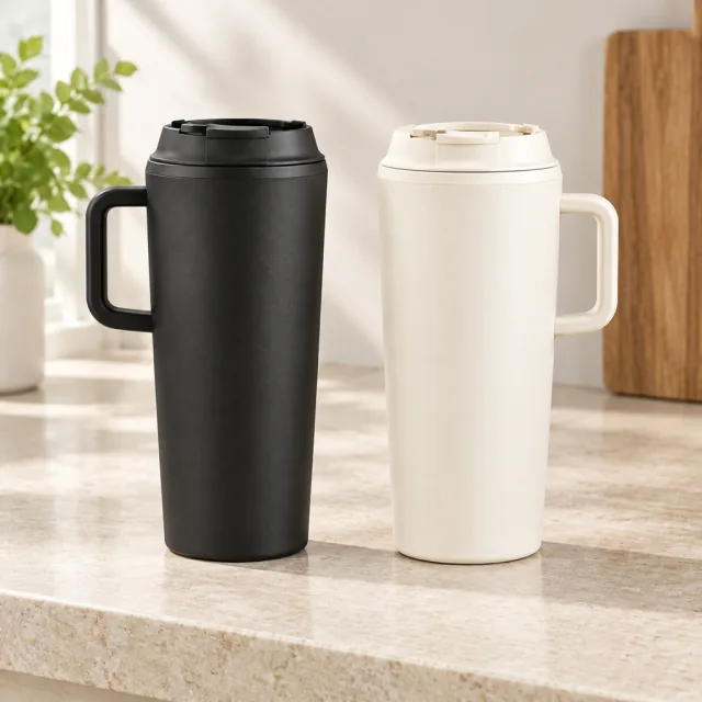 Matte black and warm cream insulated tumblers standing side by side on a stone shelf.