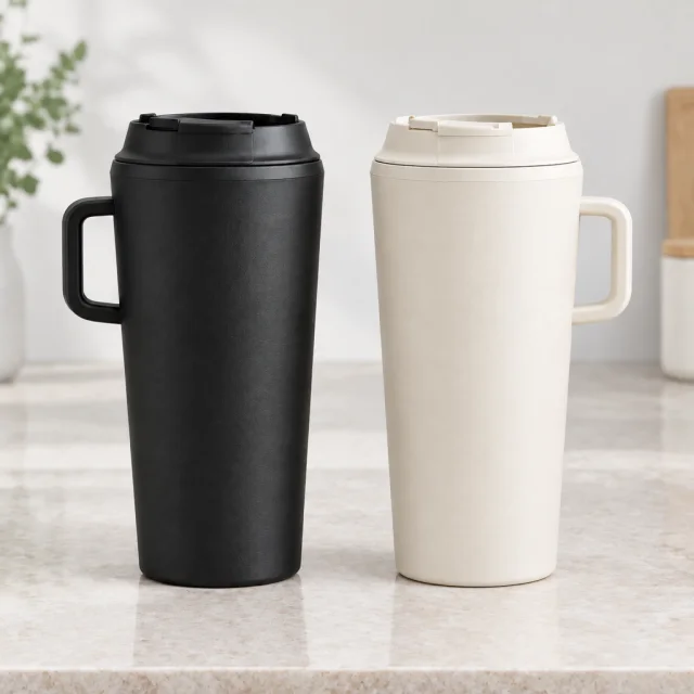 The same matte black and warm cream insulated tumblers on a pale stone countertop.