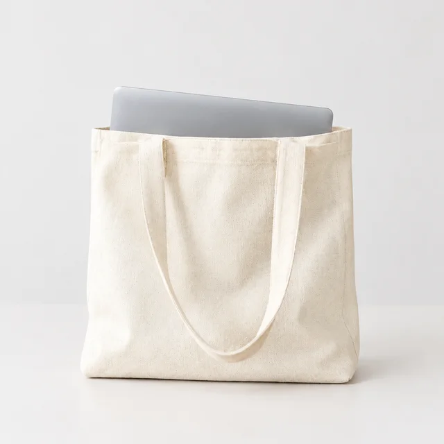 Natural canvas tote holding a laptop, shown fully on a pale background.
