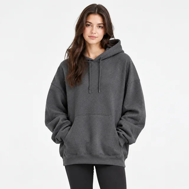 Adult wearing a plain charcoal oversized hoodie against a light background.