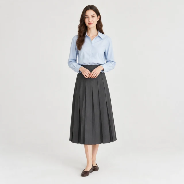 Adult model in a plain pale blue blouse and charcoal pleated midi skirt with dark brown leather flats.