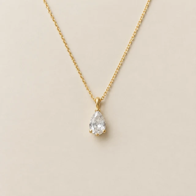 Close view of a necklace chain and pendant against a light background.