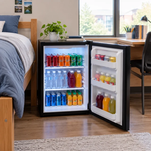 Mini fridge stocked with drinks in a dorm room.