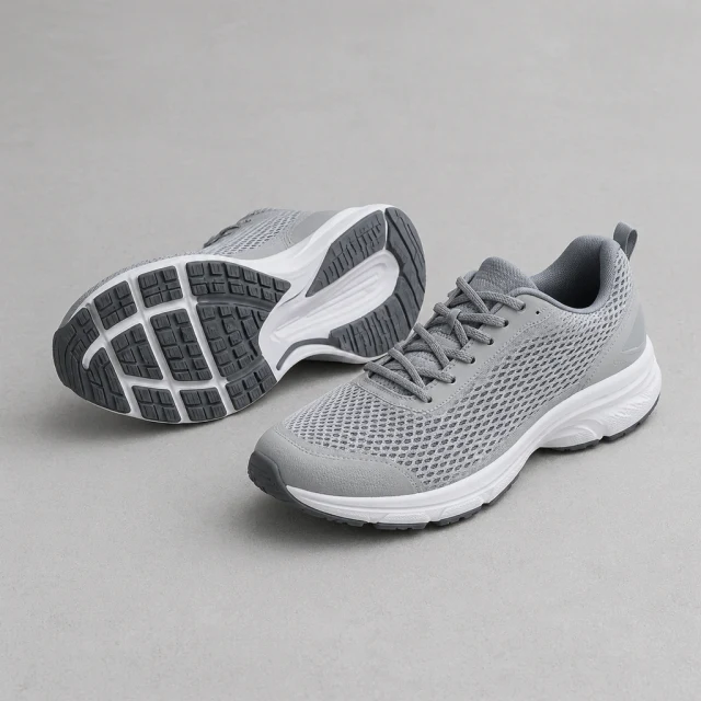 Gray mesh running shoe turned to show its patterned sole on a plain floor.