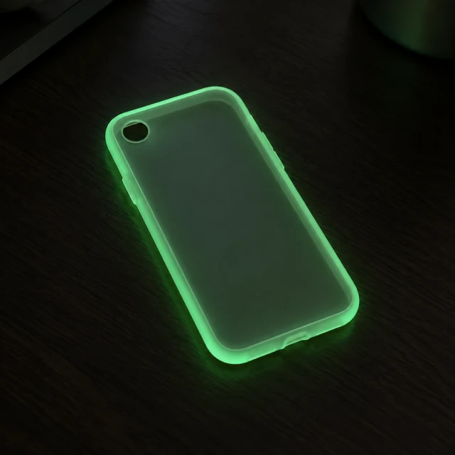 Plain glow-in-the-dark flexible phone case with one circular camera opening in a dim room.