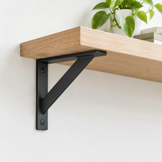 Simple metal floating shelf bracket mounted on a pale wall with the bracket shape clearly visible.