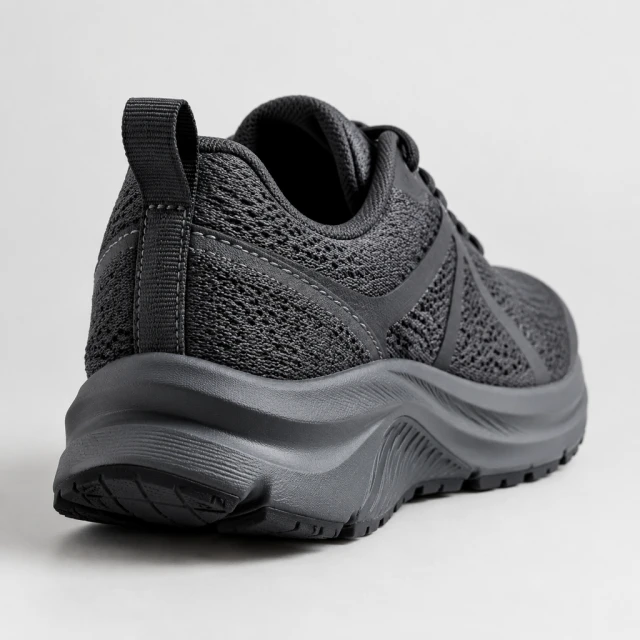 Charcoal running shoe heel and stitching in sharp focus on a clean neutral surface.