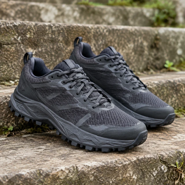 Dark charcoal trail running shoes on weathered outdoor steps, complete pair visible, not canvas low-top sneakers.
