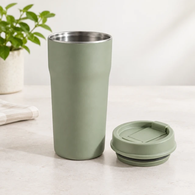 Matte sage travel mug with a separate matching lid displayed on a clean pale tabletop, no lettering.