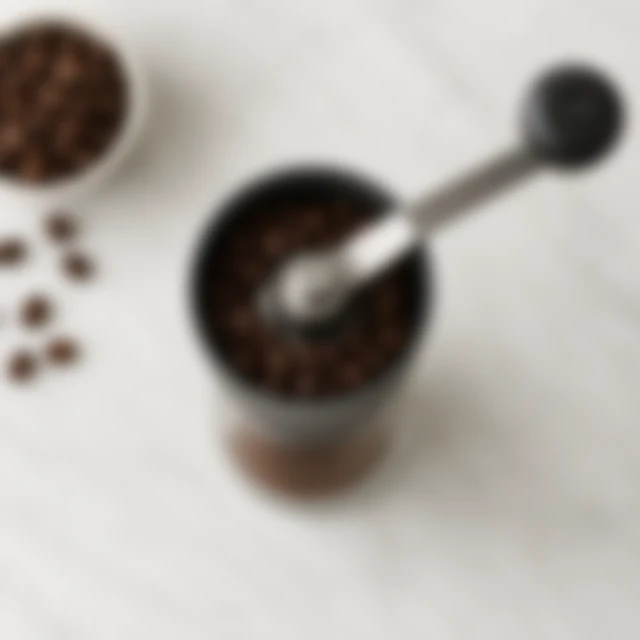 Coffee grinder and beans softened out of focus on a pale counter.