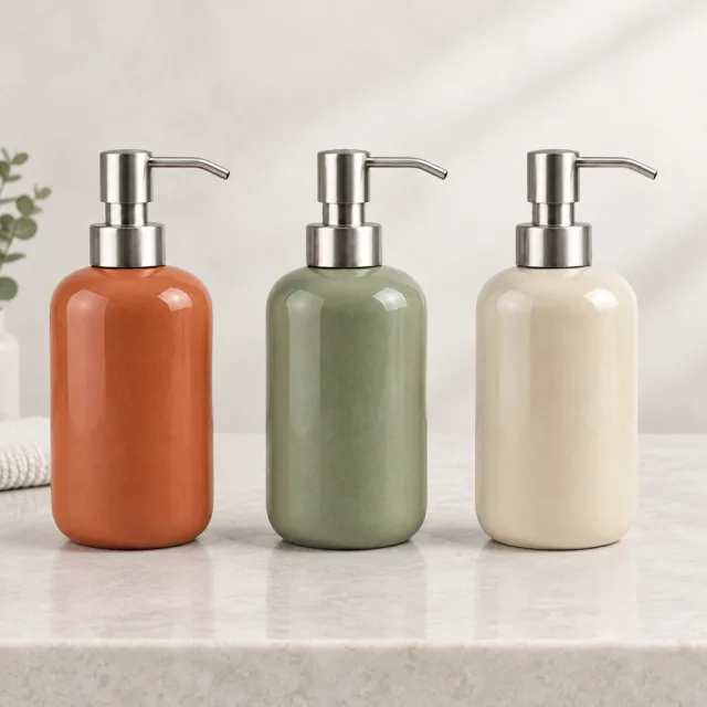 Square photo of three ceramic soap dispensers in muted terracotta, sage, and cream finishes.