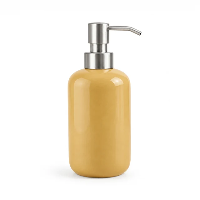 Unbranded ceramic soap dispenser in soft ochre glaze with a brushed metal pump on white.