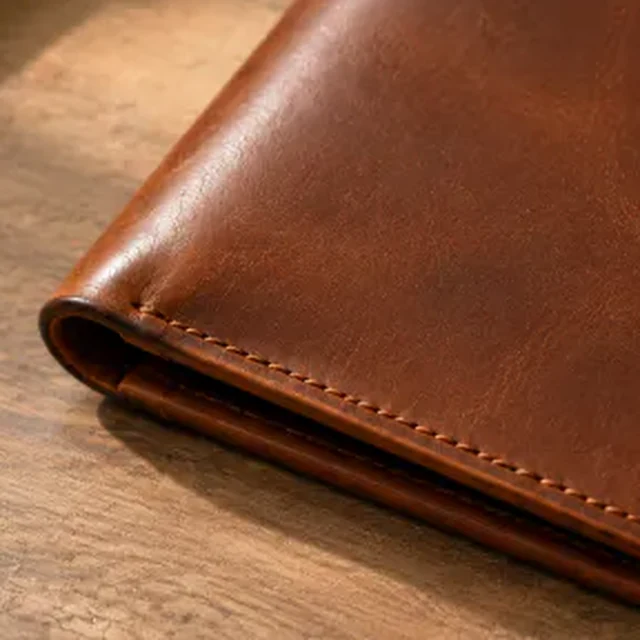 Square macro view of a brown leather wallet corner and edge finish.