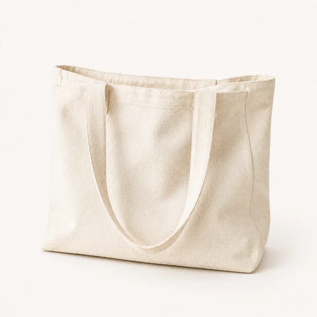 Natural canvas tote bag standing alone on a pale studio background.