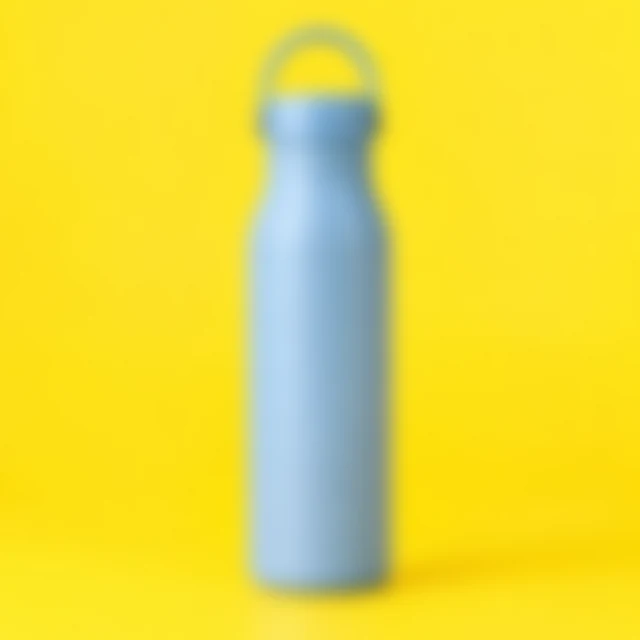 Blue bottle and cap softly blurred on a bright yellow background.