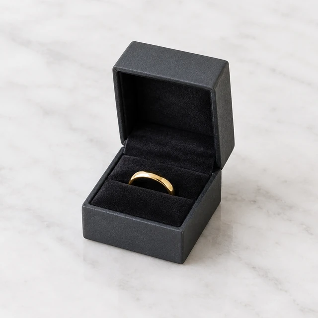 Small jewelry box opened to a simple gold ring on velvet.