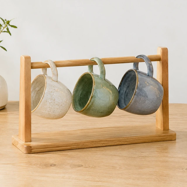 Handmade ceramic mugs lined up on a drying rack.